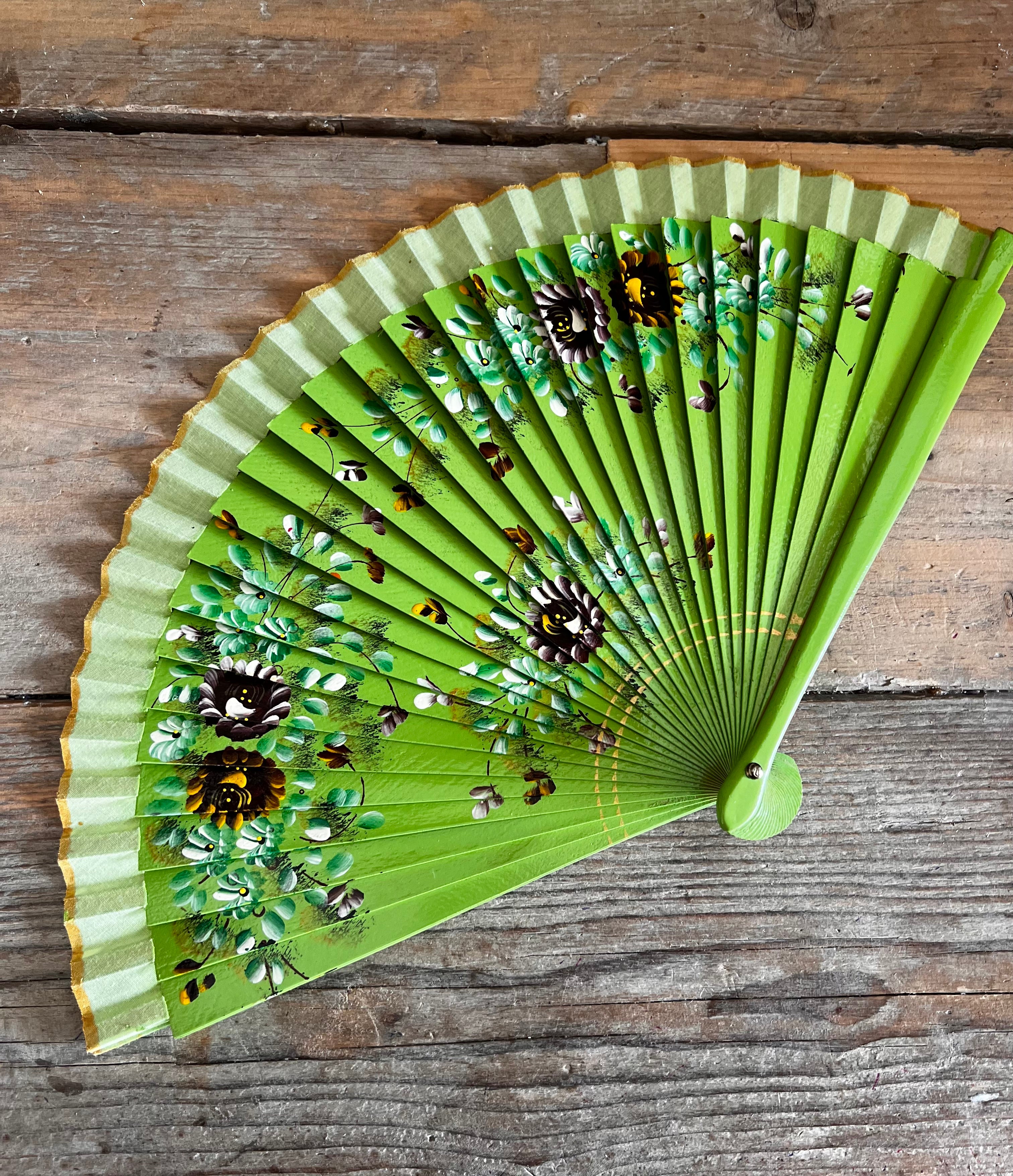 Groene handbeschilderde waaier met bloemen. hout