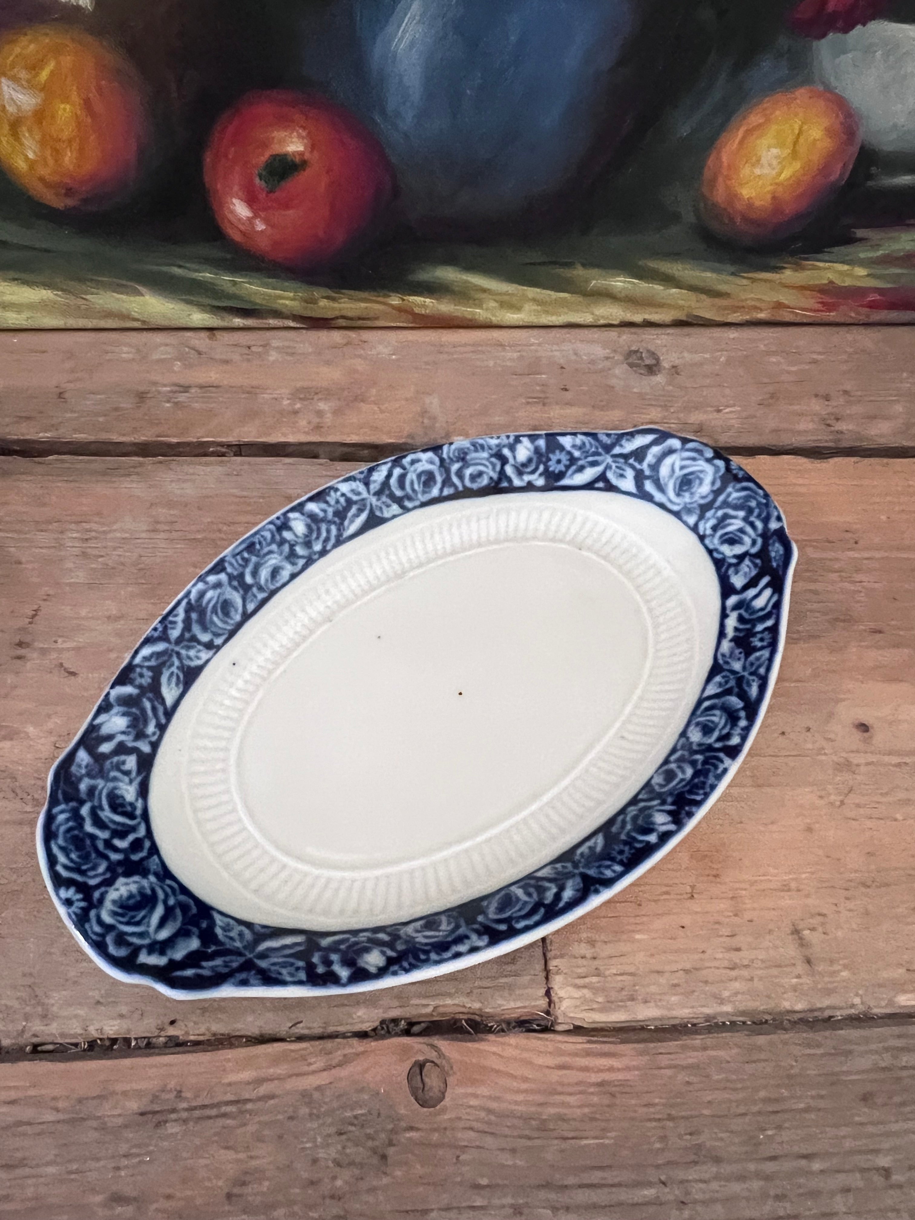 Zuurschaaltje Mosa Mosa serveerschaal, vintage serveerschaal, Mosa vintage servies, serveerschaal met bloemenrand, blauw-witte rozen servies, vintage servies keramiek, bloemenmotief servies, romantisch servies, keramische serveerschaal, decoratieve serveerschaal.