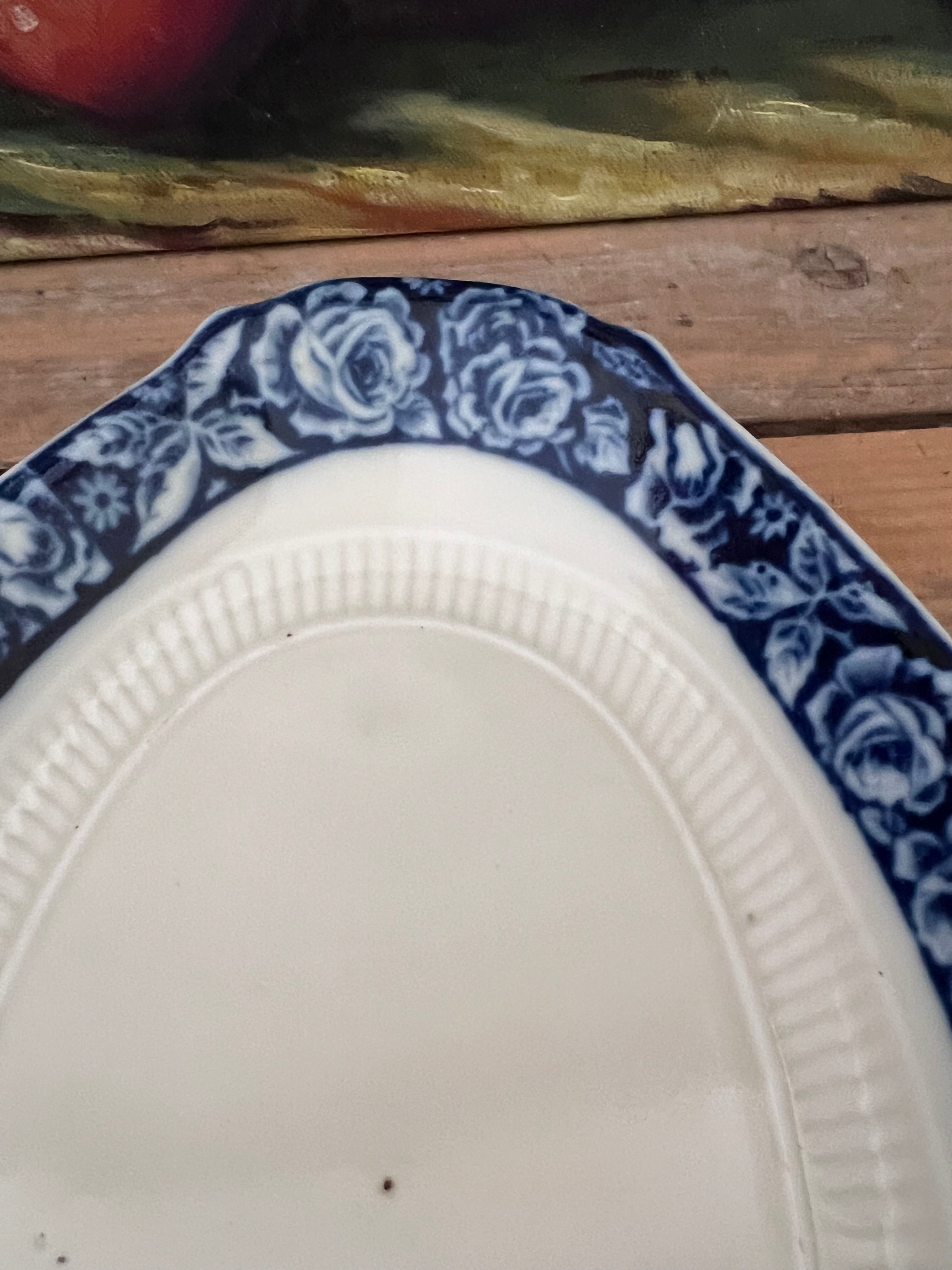 Zuurschaaltje MosaMosa serveerschaal, vintage serveerschaal, Mosa vintage servies, serveerschaal met bloemenrand, blauw-witte rozen servies, vintage servies keramiek, bloemenmotief servies, romantisch servies, keramische serveerschaal, decoratieve serveerschaal.