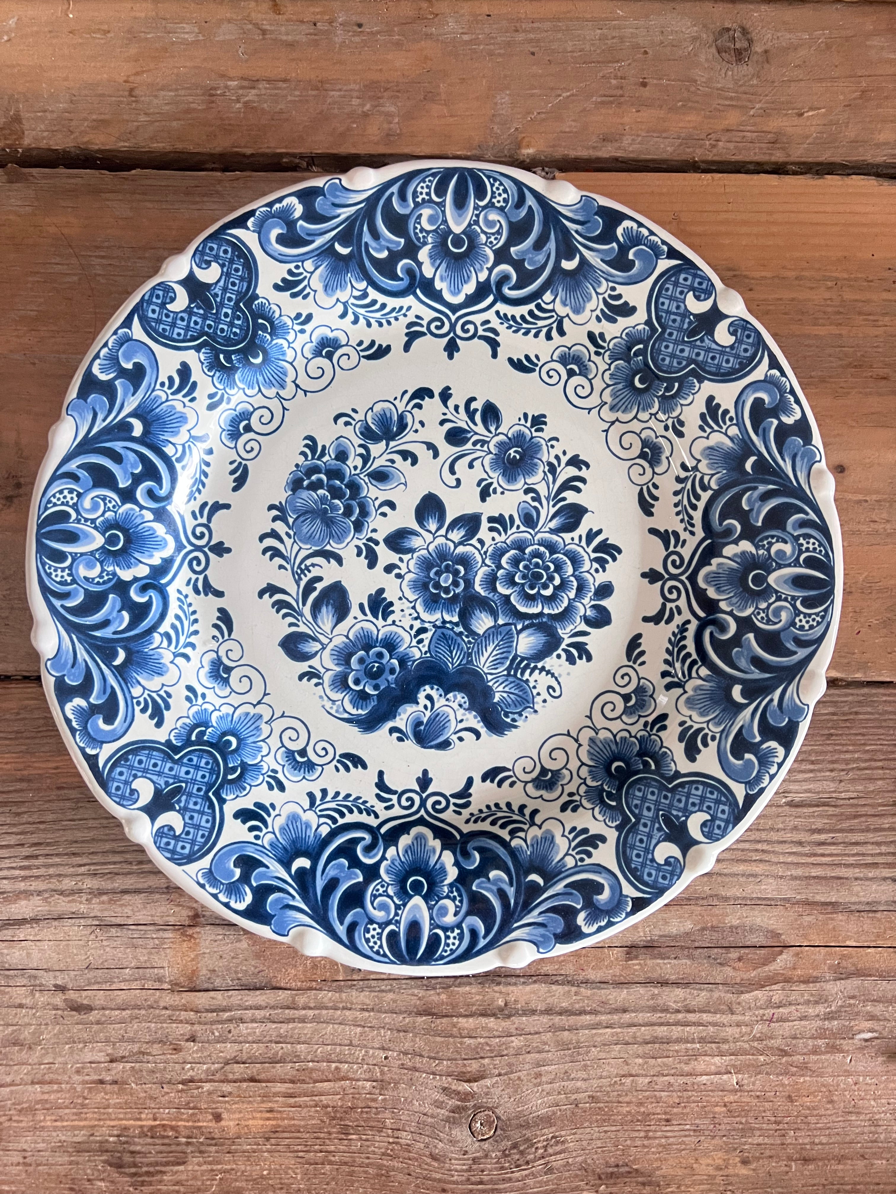 Dit prachtig handbeschilderde wandbord is afkomstig uit de wereldberoemde fabriek uit Delft, de Porceleyne Fles en toont een klassiek boeket in vaas. Het bord staat symbool voor traditioneel Nederlands vakmanschap en is een waardevol decoratief kunstwerk voor aan de muur. 
Perfect voor liefhebbers van Delftsblauw en authentieke porseleinen wanddecoratie. 
Diameter 28 centimeter