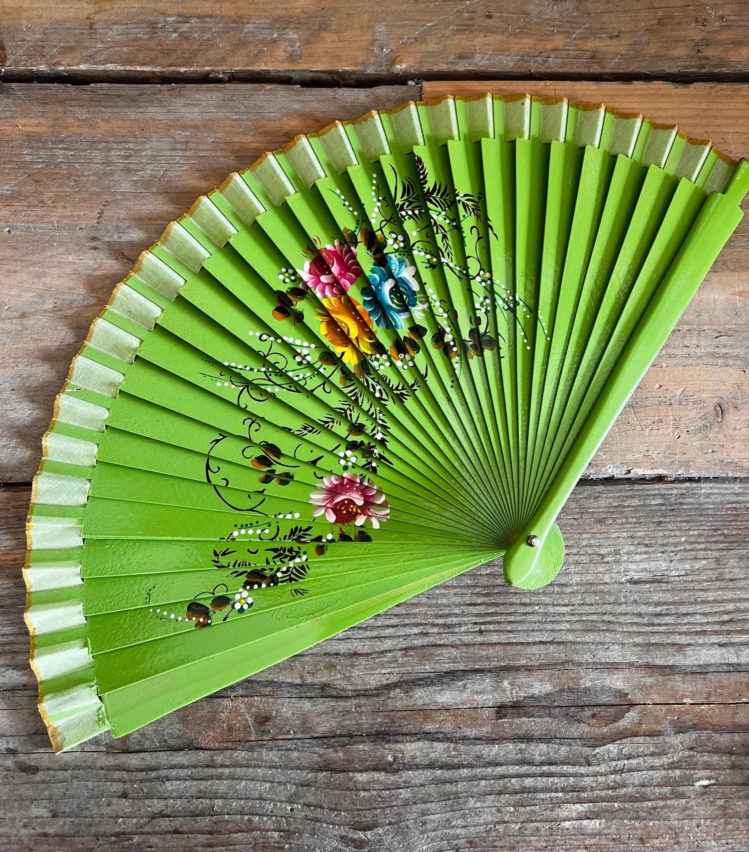 Groene handbeschilderde waaier met bloemen. hout