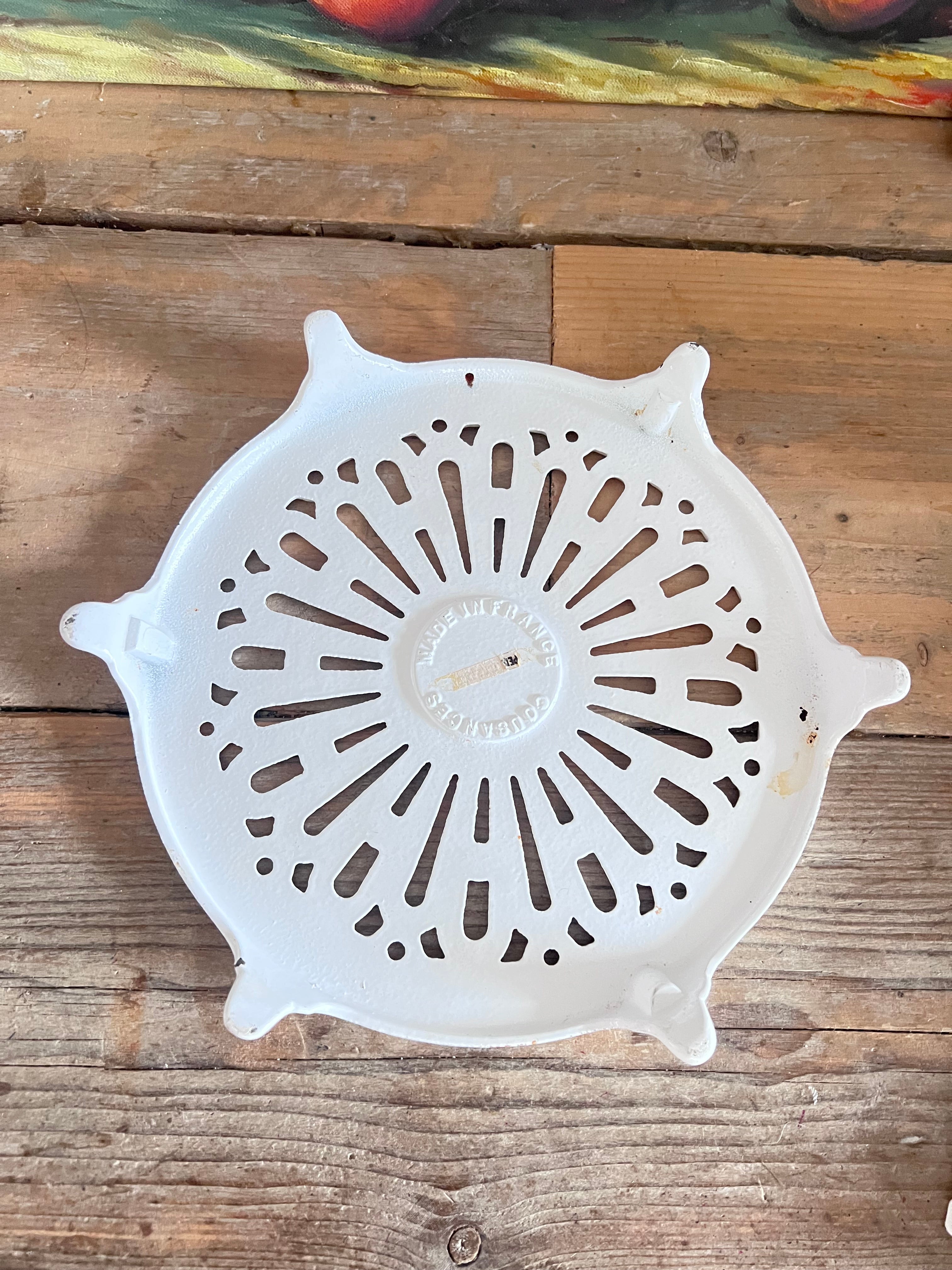 vintage Le Creuset onderzetter, Cousances gietijzeren onderzetter, geëmailleerde onderzetter wit, Franse Le Creuset accessoires, gietijzeren onderzetter vintage, Le Creuset keukenaccessoires, ronde onderzetter gietijzer, duurzame onderzetter, Le Creuset Cousances vintage, hittebestendige onderzetter