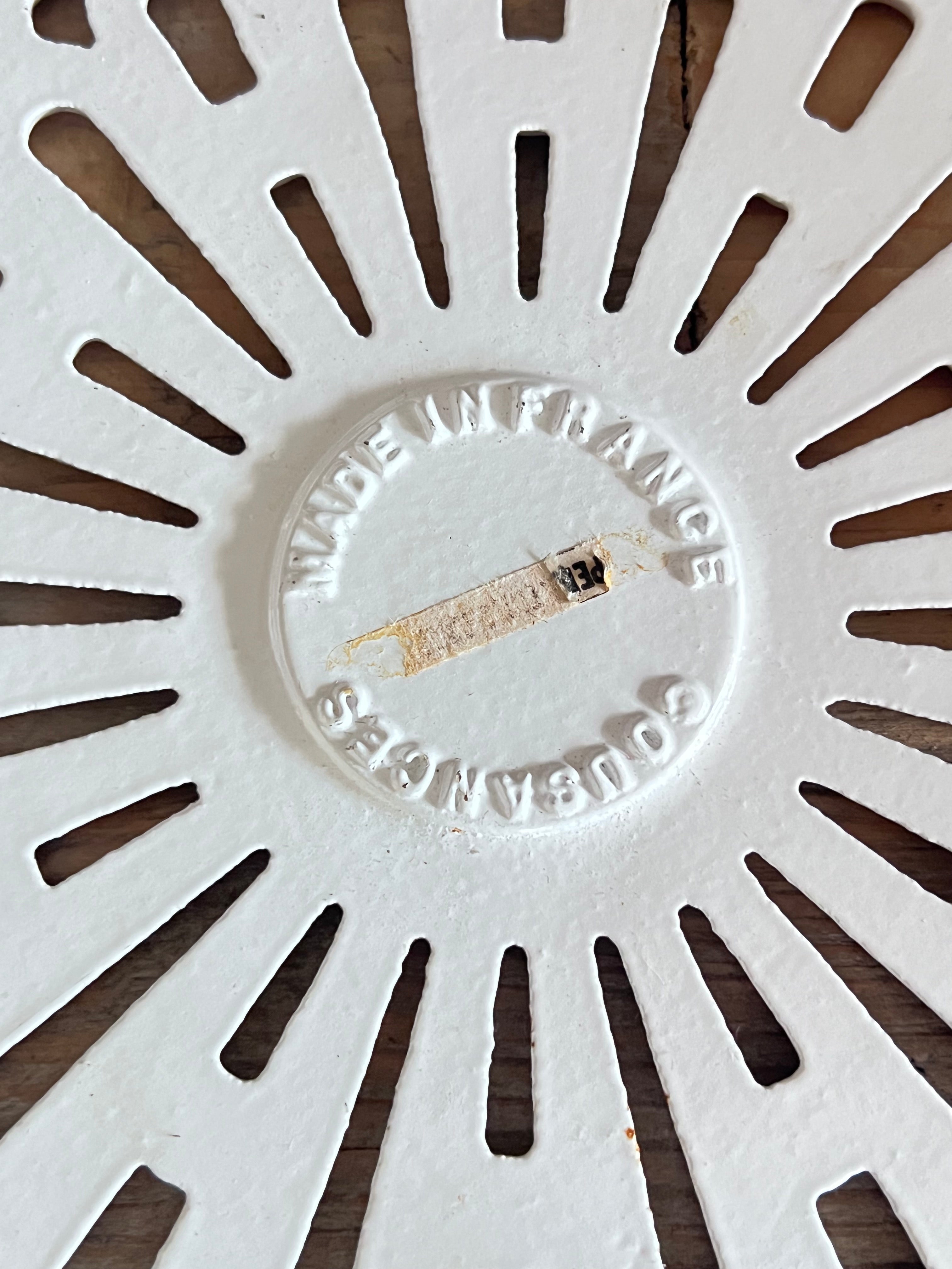 vintage Le Creuset onderzetter, Cousances gietijzeren onderzetter, geëmailleerde onderzetter wit, Franse Le Creuset accessoires, gietijzeren onderzetter vintage, Le Creuset keukenaccessoires, ronde onderzetter gietijzer, duurzame onderzetter, Le Creuset Cousances vintage, hittebestendige onderzetter