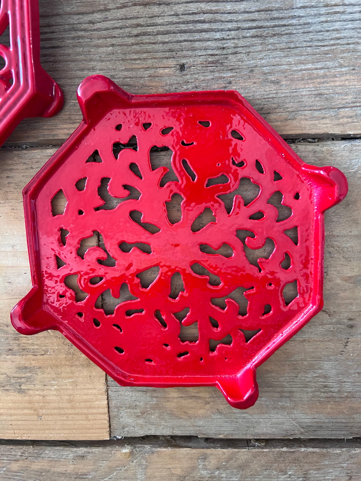 rode onderzetter gietijzer, vintage onderzetter pannen, gietijzeren onderzetter retro, onderzetter voor hete pannen, vintage keukenaccessoires, gietijzeren pannendrager, retro pannenonderzetter, keukendecor vintage.