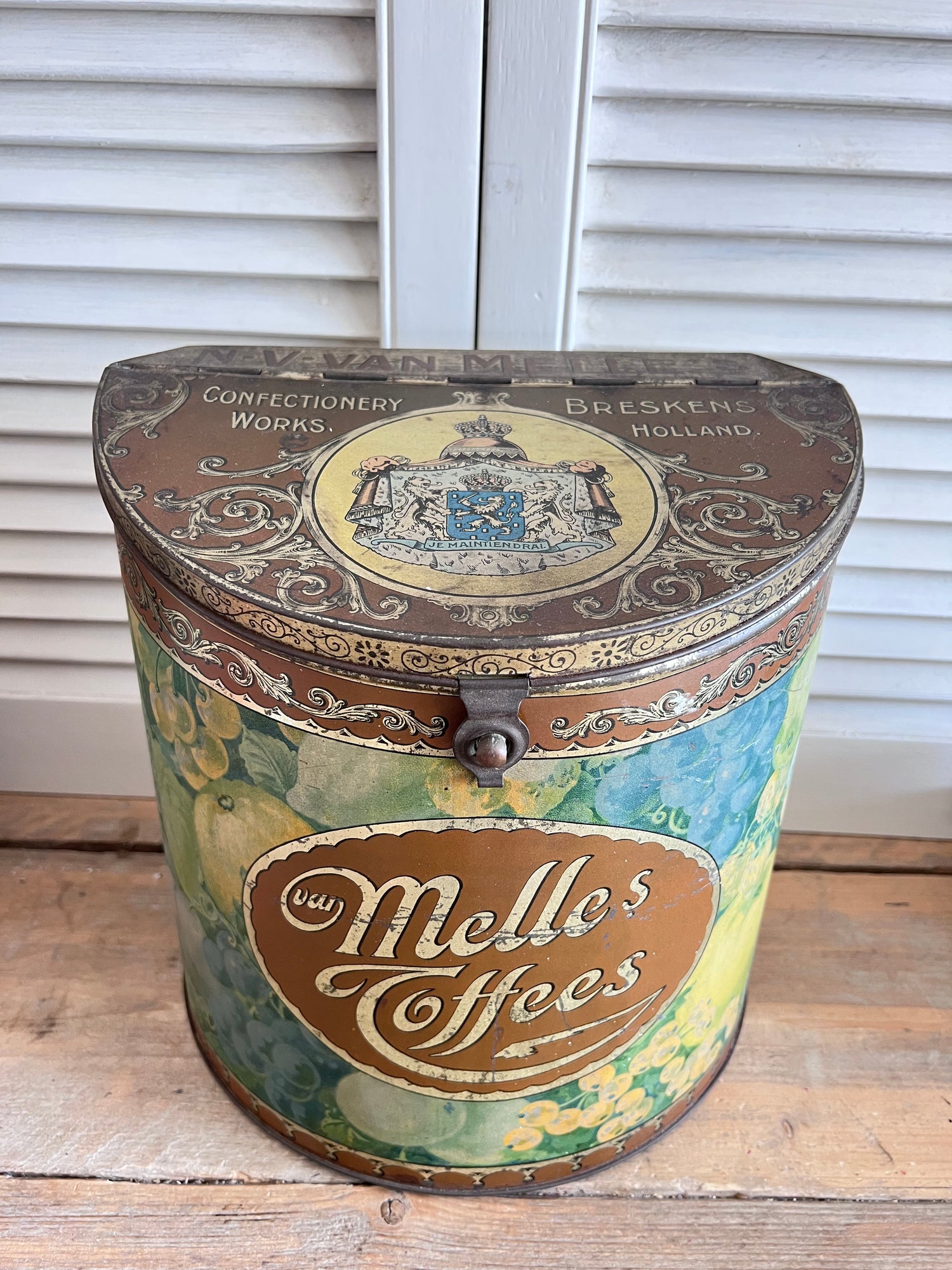 vintage Van Melle toffeeblik, antiek toffeeblik, Van Melle snoepblik, half cilindrisch blik, fruitdecoratie blik, toffeeblik met scharnierdeksel, retro snoepblik, vintage snoepblik, antieke snoepverpakking, collectible toffeeblik, snoepblik uit 1915-1930